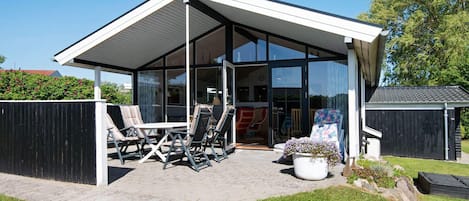 Uma casa moderna com varanda coberta, área de estar externa e porta de vidro que dá para o interior.