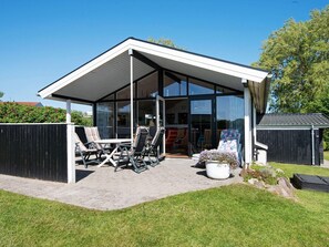 A modern house with a covered patio, outdoor seating, and a glass door leading to the interior. - 4 Person Holiday Home in Broager (Broager)