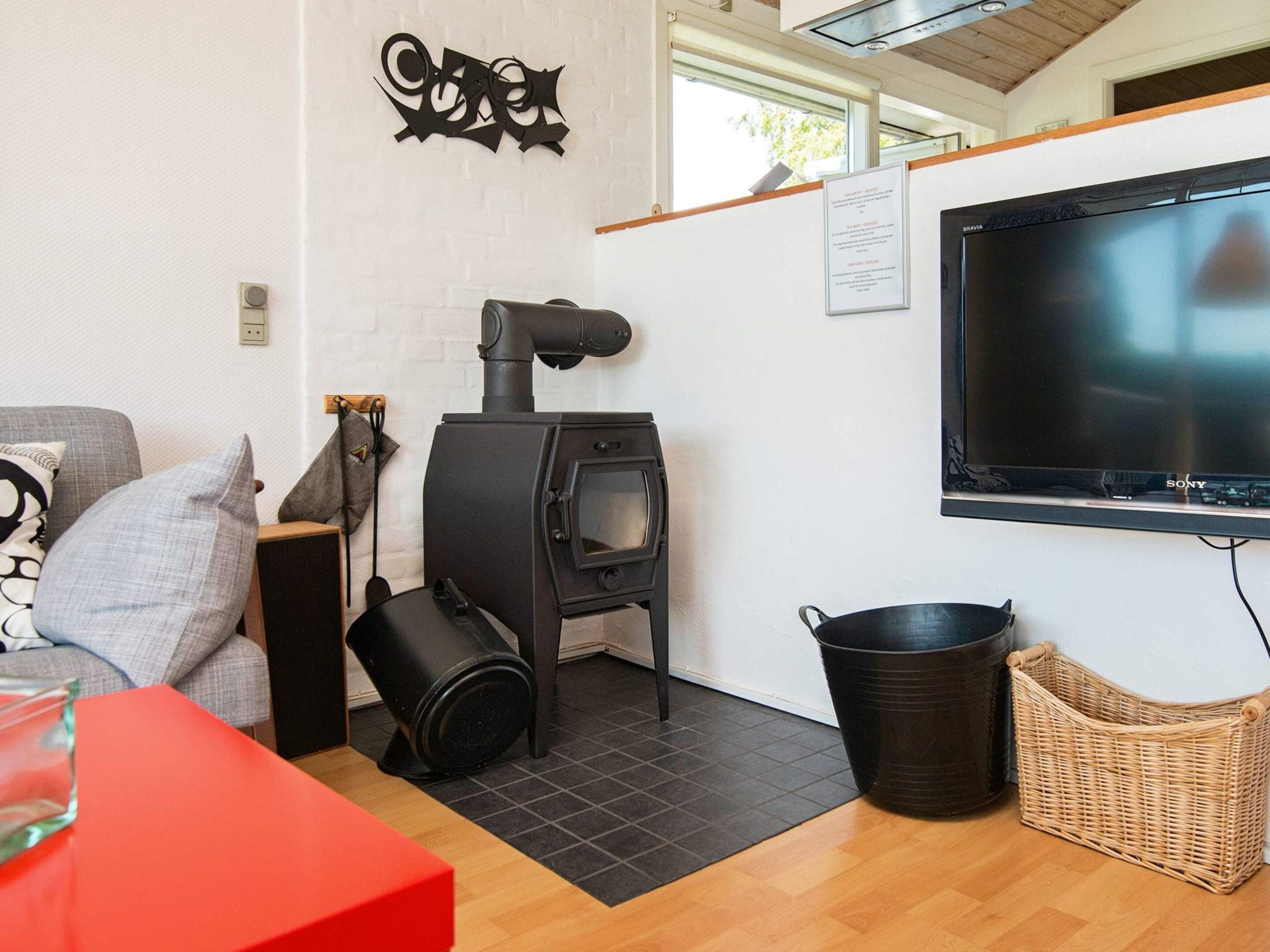 A cozy living area with a fireplace, a flat-screen TV mounted on the wall, and a comfortable seating area with cushions.