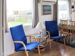 A room with two blue chairs, a small table with a lamp, and a painting on the wall. - 4 Person Holiday Home in Broager (Broager)
