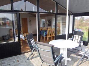 An outdoor patio with a round table and chairs, a dining area with a table and chairs, and a view of the surrounding landscape. - 4 Person Holiday Home in Broager (Broager)