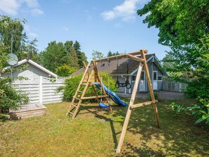 A wooden swing set with a slide in a backyard.