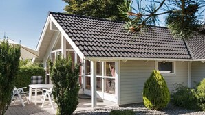 A house with a sloped roof, a covered porch, and a patio with outdoor furniture. - Pleasing Holiday Home in Ebeltoft near Sea (Ebeltoft)