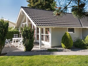 A house with a sloped roof, a covered porch, and a patio with outdoor furniture. - Pleasing Holiday Home in Ebeltoft near Sea (Ebeltoft)