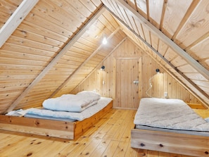 A wooden attic bedroom with two beds, a wooden door, and a sloped ceiling. - 7 Person Holiday Home in Kolind-by Traum (Kolind)