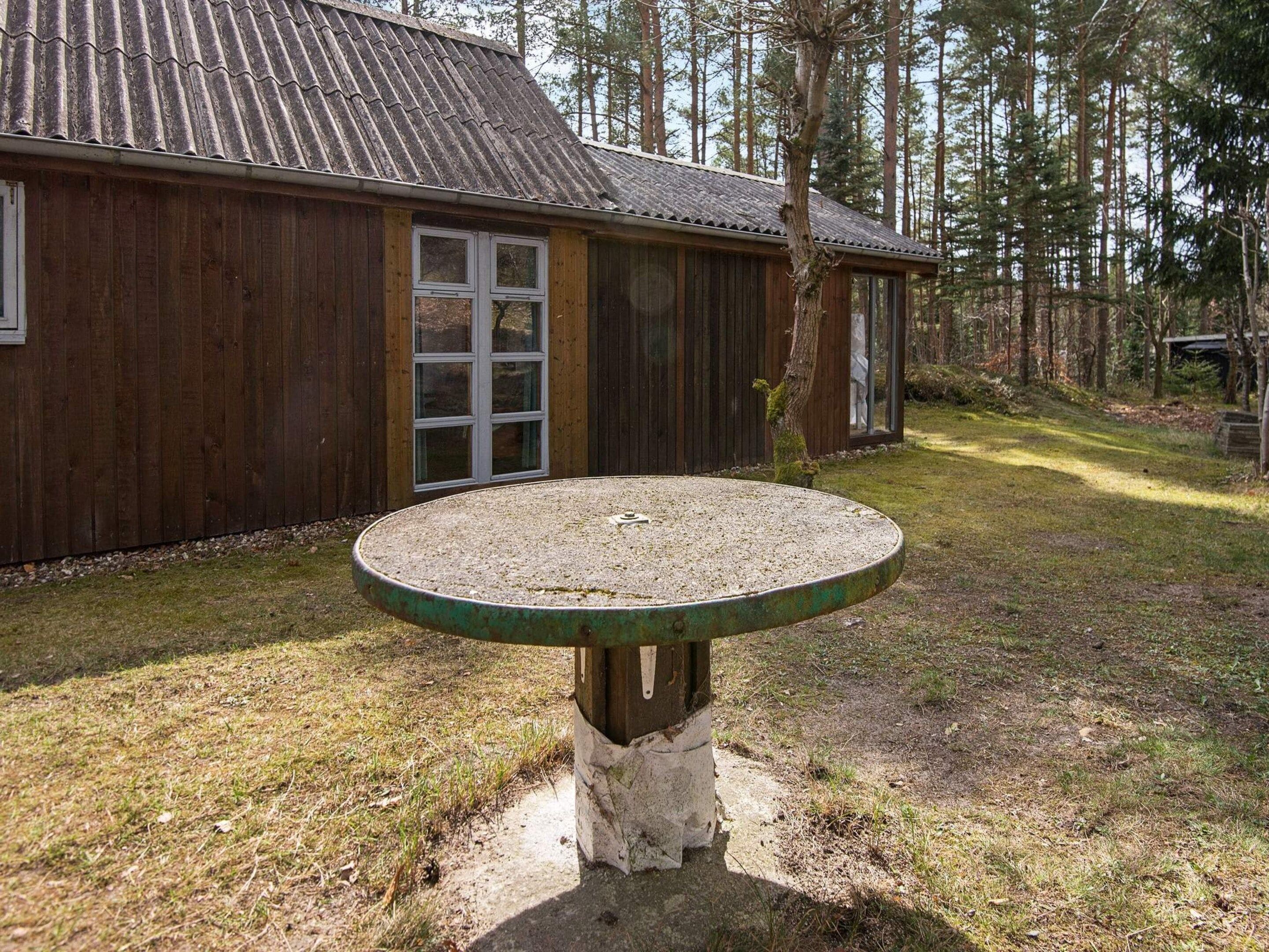 A wooden building with a gravel patio and a table in front.