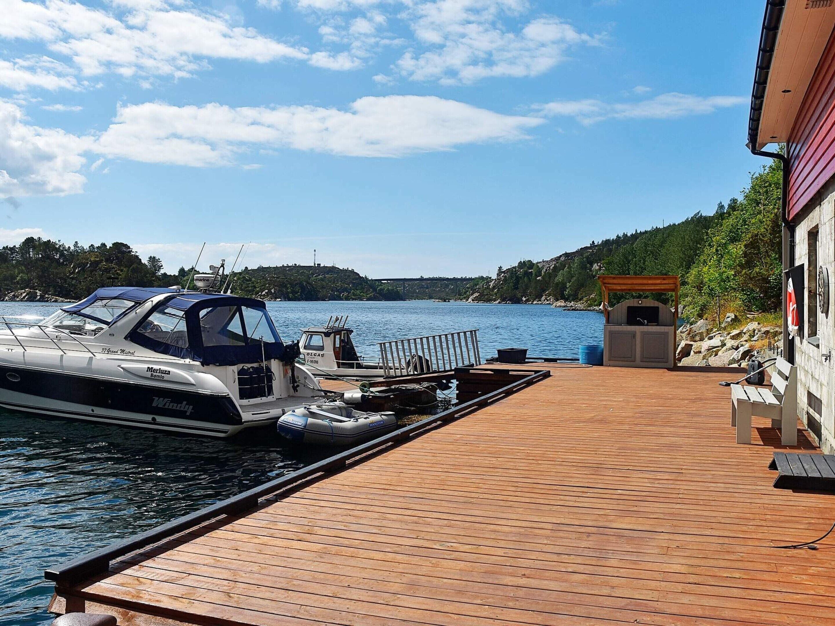 Eine Holzstege führt zu einem Boot, einem Grillplatz und einem Gebäude mit Blick auf das Wasser.