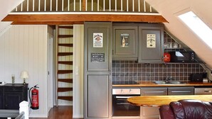 A compact kitchen with a wooden table, a built-in oven, and a microwave. There is a fire extinguisher and a sign on the wall. - 4 Star Holiday Home in Urangsvag (Bomlo)