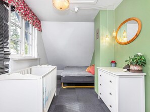 A room with a bed, a crib, a dresser, a mirror, and a window with blinds. - 19 Person Holiday Home in Logstor-by Traum (Logstor)