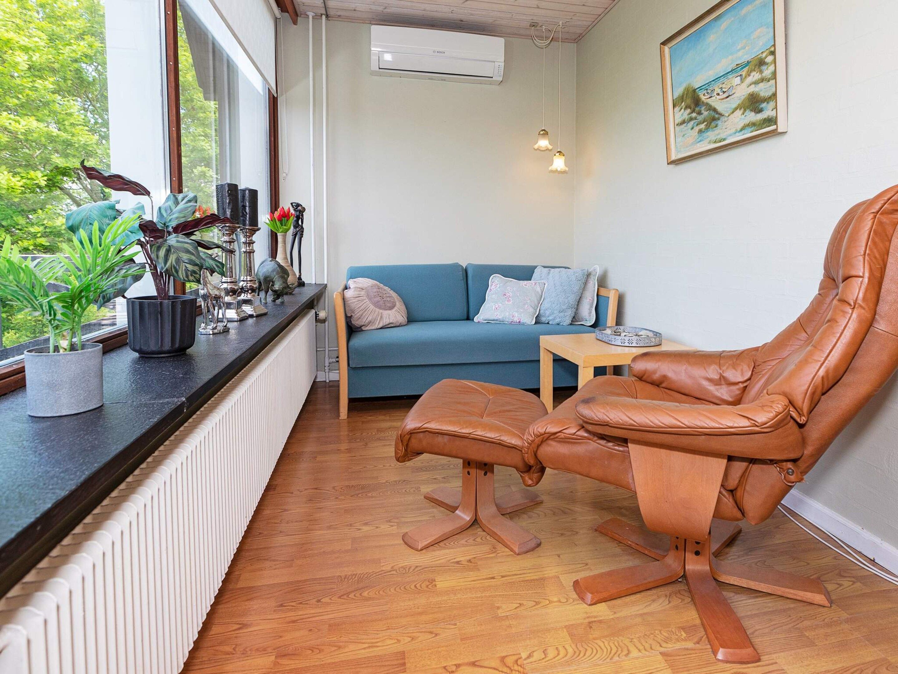 A room with a leather chair, a blue sofa, a small table, and a radiator.
