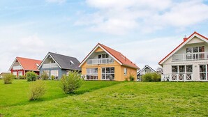 Une rangée de maisons aux toits rouges et aux murs blancs, construite sur une colline verdoyante.