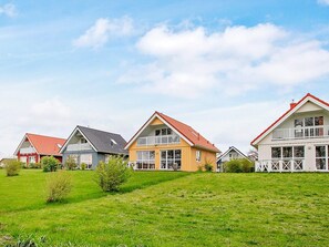 En rad hus med röda tak och vita väggar, belägna på en grönskande kulle.