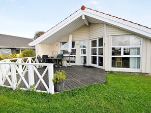 Ett tvåvåningshus med en inglasad uteplats, en inhägnad terrass och en gräsyta.