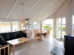 Um quarto amplo com área de jantar, sofá, televisão e janelas grandes.