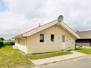 A single-story building with a pitched roof, a satellite dish, and a small porch area.