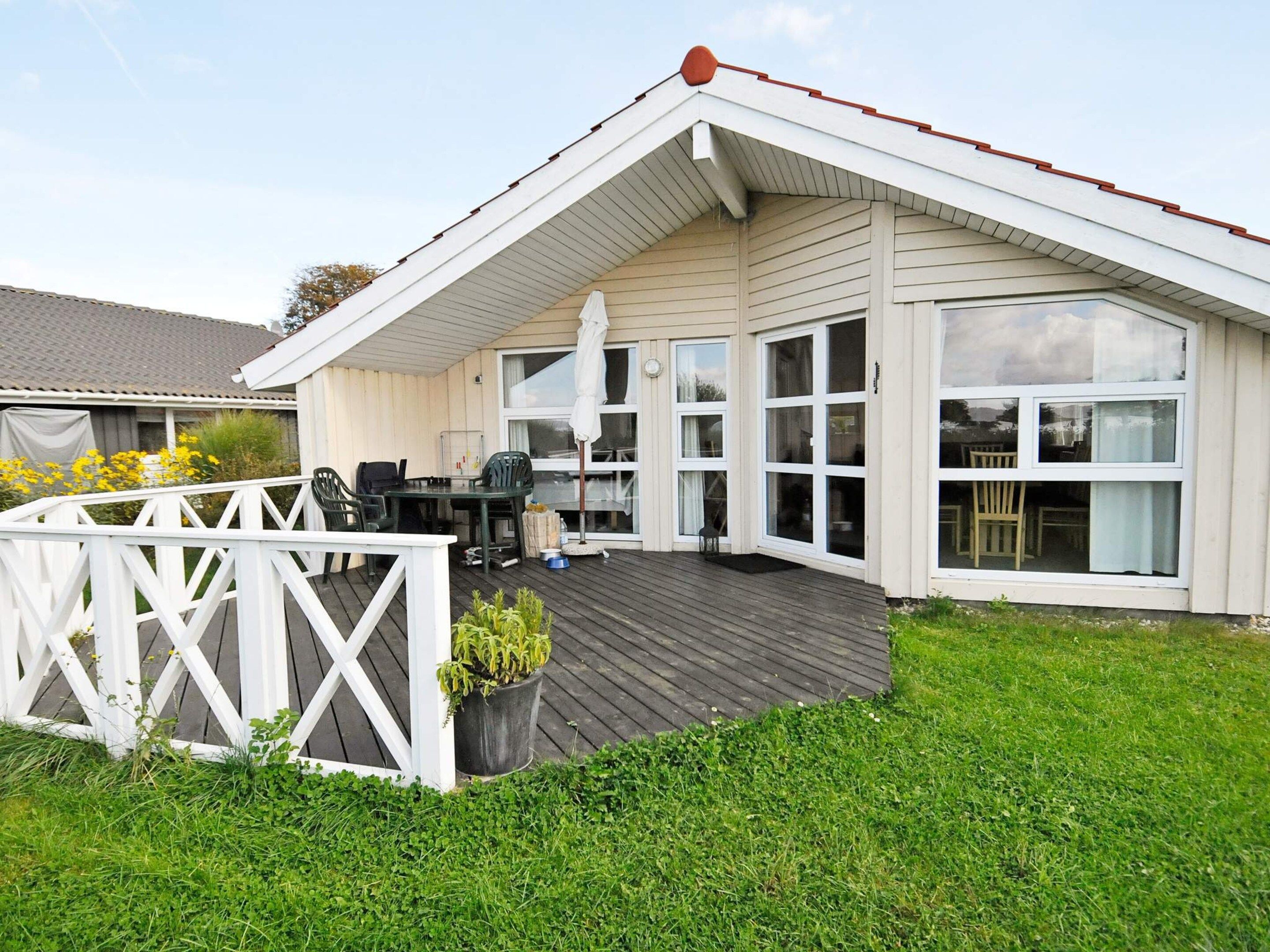 A two-story house with a covered patio, a fenced deck, and a grassy yard.