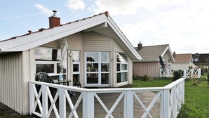 A single-story house with a white exterior, a covered porch with a white railing, and a small deck area. - Holiday Home in Gelting (Gelting)