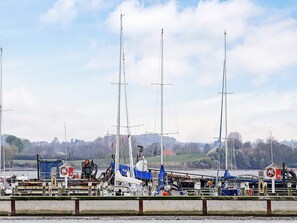 A marina with multiple sailboats docked, a lifebuoy, and a small building with a red and white sign. - Holiday Home in Gelting (Gelting)