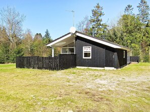 A small, single-story building with a sloped roof, a satellite dish, and a window with a sign.