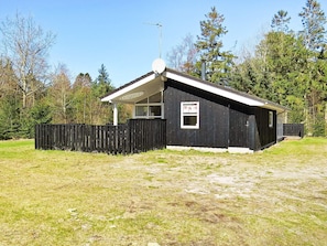 A small, single-story building with a sloped roof, a satellite dish, and a window with a sign.