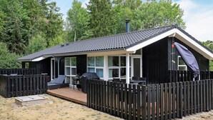 A cabin with a deck, a covered outdoor seating area, and a fenced yard. - 5 Star Holiday Home in Hals (Hals)