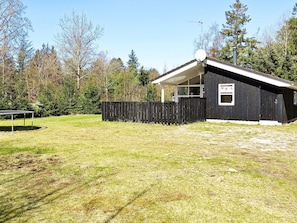 A small, single-story building with a fenced yard, a satellite dish, and a signboard.