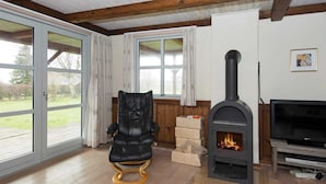 A living room with a black leather chair, a fireplace, and a TV. - 5 Person Holiday Home in Ebeltoft (Ebeltoft)