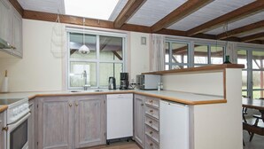 A compact kitchen with wooden cabinets, a dishwasher, a microwave, and a coffee maker. - 5 Person Holiday Home in Ebeltoft (Ebeltoft)
