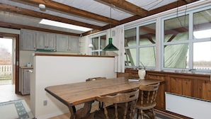 A rustic kitchen with wooden beams, a large island with chairs, and a window overlooking a garden. - 5 Person Holiday Home in Ebeltoft (Ebeltoft)