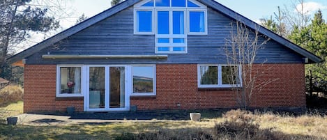 Une maison de plain-pied avec un toit à pignon, un porche à l’avant et une façade en briques.