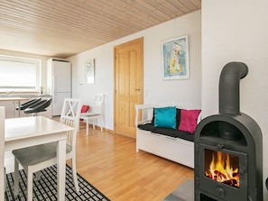 A cozy living room with a fireplace, a dining area, and a wooden ceiling. - 4 Star Holiday Home in Thyholm (Thyholm)