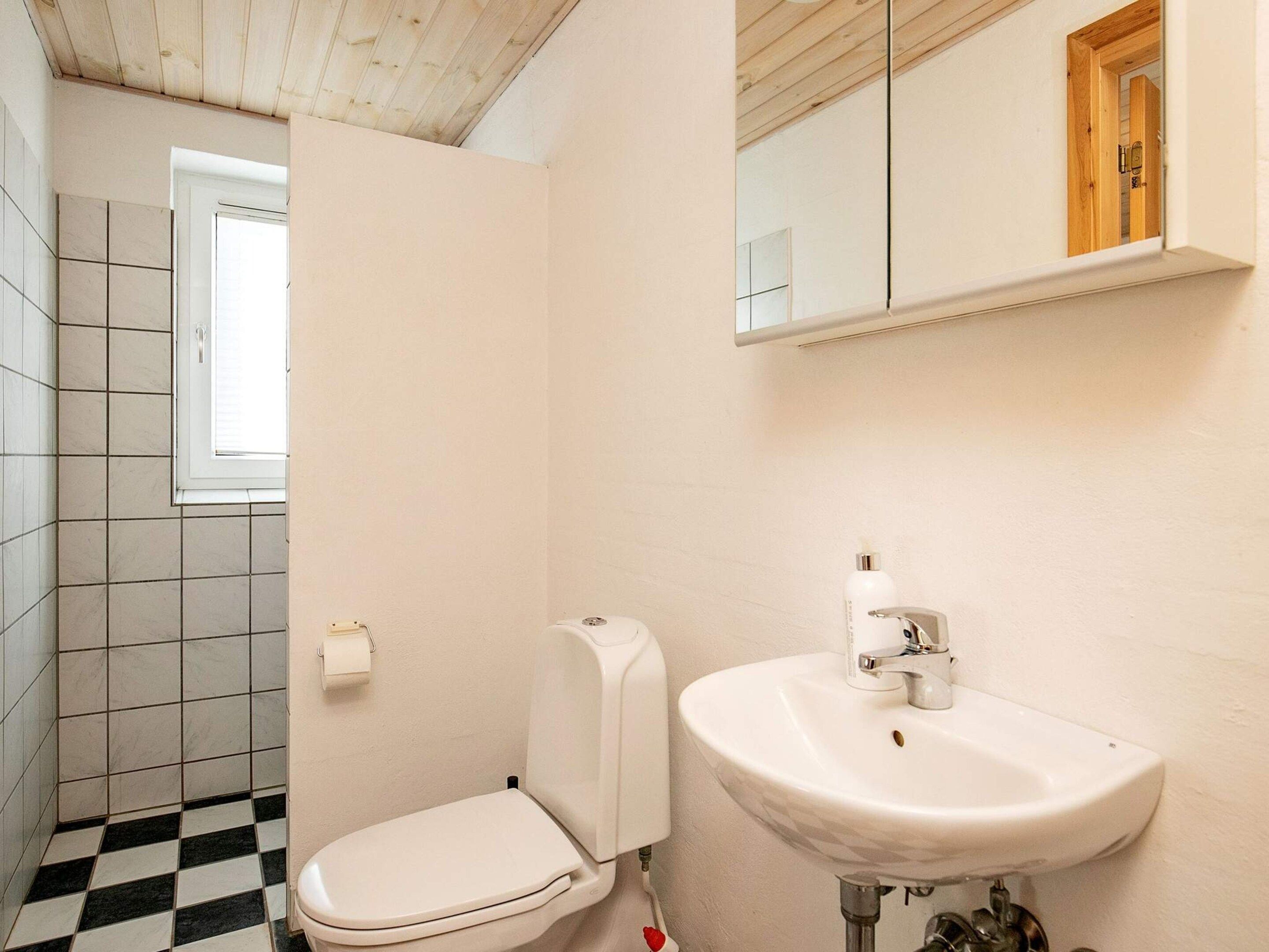 Ein kleines Badezimmer mit Toilette, Waschbecken und Fenster.