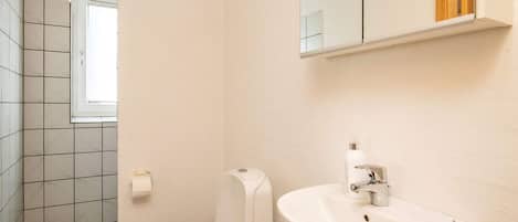 A small bathroom with a toilet, sink, and a window.