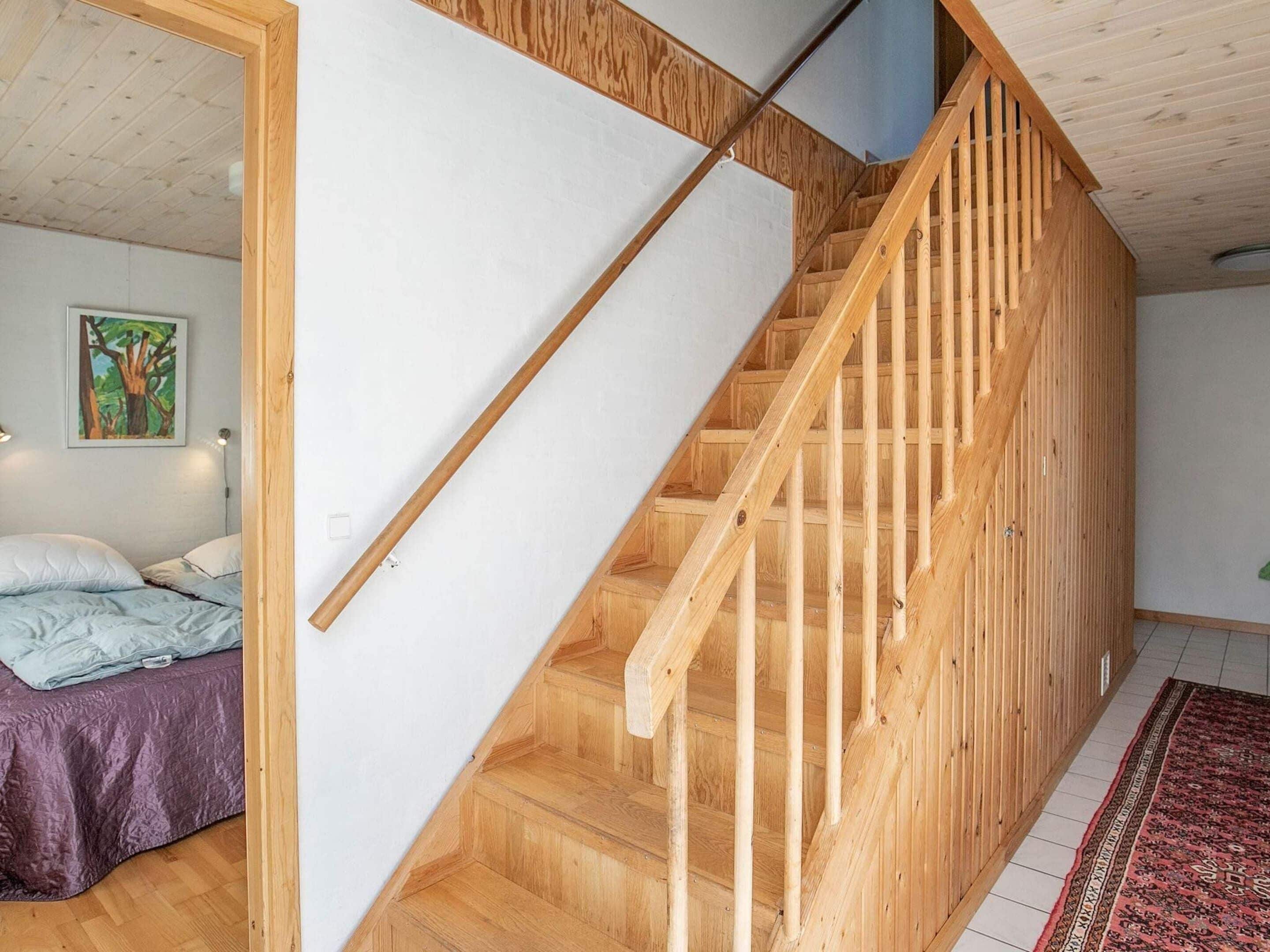 A wooden staircase in a room with a bed and a painting on the wall.