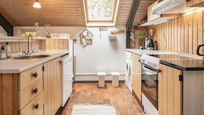 Eine kleine Küche mit Holzausstattung, einem Spülbecken, einem Fenster und einer Waschmaschine.