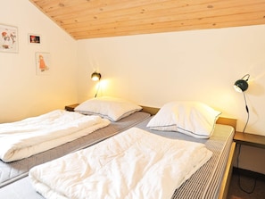 A room with two single beds, each with a pillow and a blanket, a wooden ceiling, and wall-mounted lamps. - 5 Person Holiday Home in Martofte (Martofte)