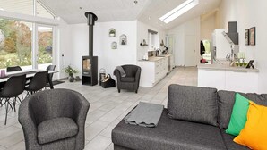 A spacious living area with a fireplace, a dining table, and a kitchen in the background. - Luxury Retreat With Pool - By Traum Ferienwohnungen (Gørlev)