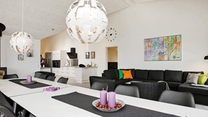 A modern living room with a dining area, a kitchen in the background, and a colorful abstract painting on the wall. - Luxury Retreat With Pool - By Traum Ferienwohnungen (Gørlev)