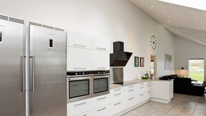 A modern kitchen with a stainless steel refrigerator, double ovens, and a large black range hood. - Luxury Retreat With Pool - By Traum Ferienwohnungen (Gørlev)