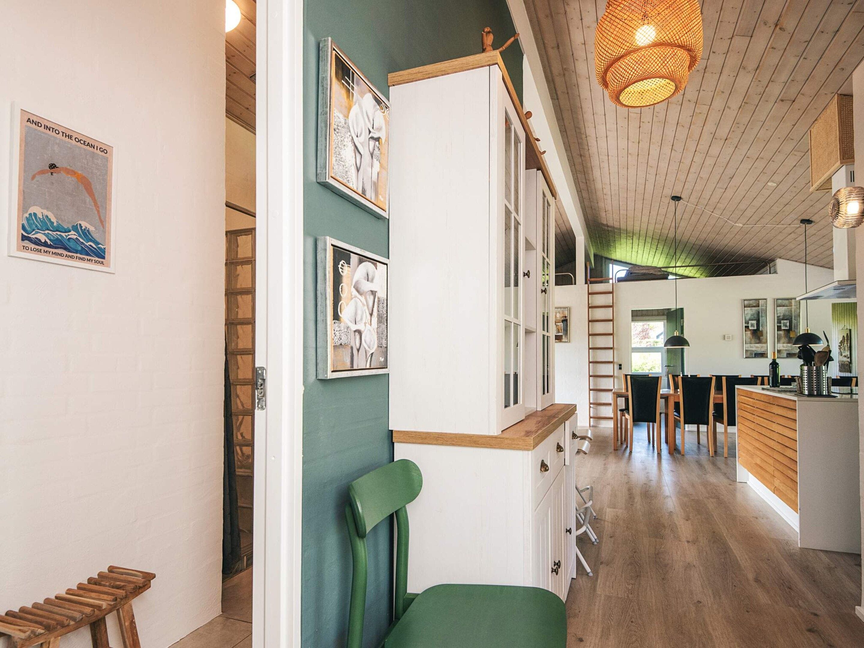 A modern interior with a wooden ceiling, a green chair, and a dining area with wooden furniture.