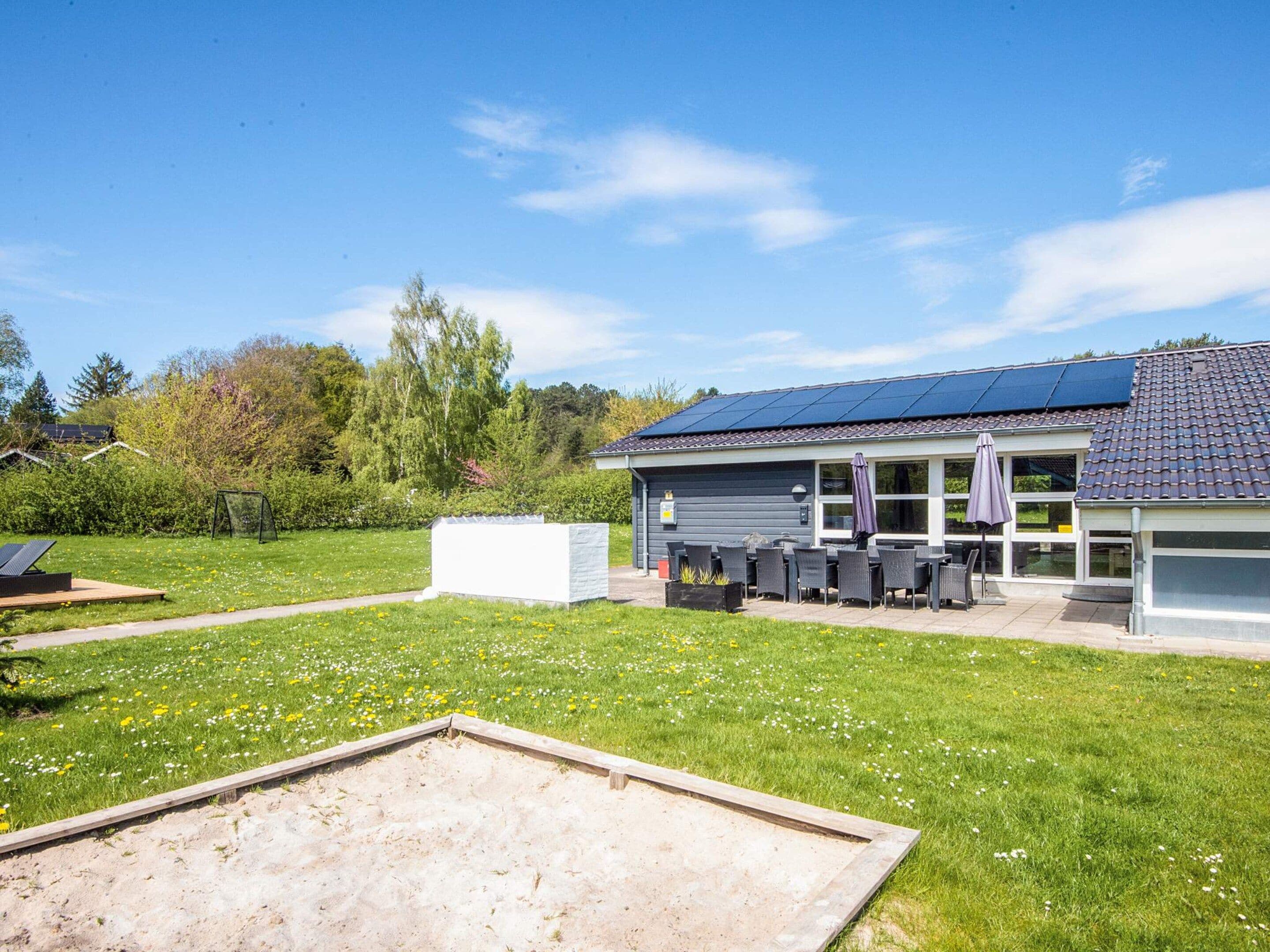 A building with a solar panel roof, outdoor seating, and a grassy yard.