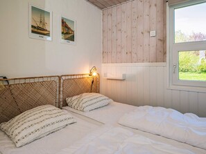 A bedroom with a wooden headboard, two pillows, a bedside lamp, and a window with a view of greenery. - 5 Star Holiday Home in Ebeltoft (Ebeltoft)