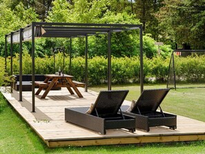 A deck with a pergola, a table, and two lounge chairs. - 5 Star Holiday Home in Ebeltoft (Ebeltoft)