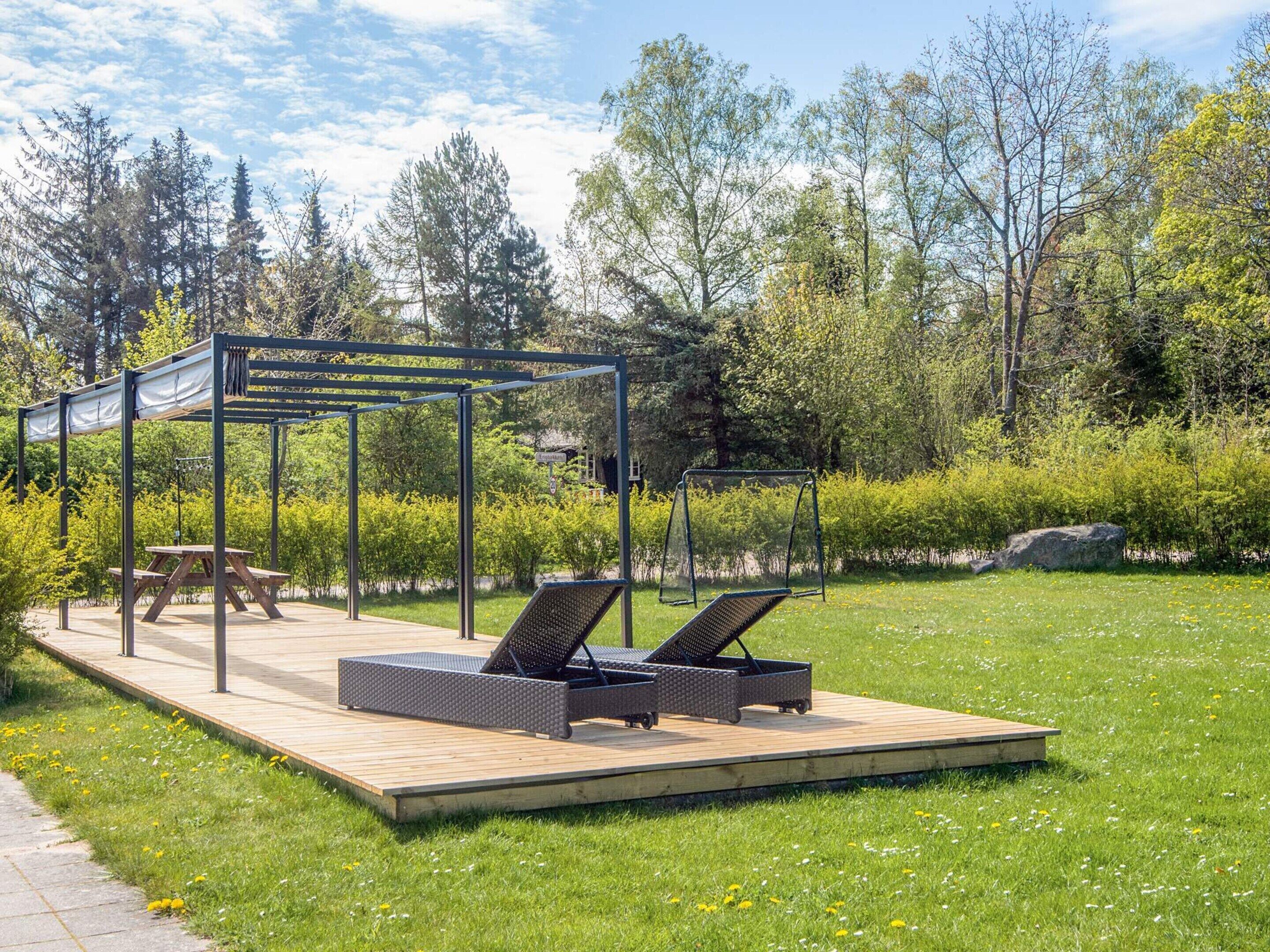 Une terrasse avec des sièges extérieurs, une table de pique-nique et une balançoire dans un parc.