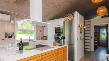 Una cocina moderna con una isla central, electrodomésticos de acero inoxidable y techo de madera.
