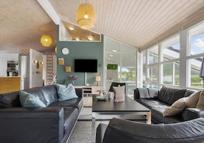 A modern living room with a sofa, coffee table, and a TV. - 5 Star Holiday Home in Ebeltoft (Ebeltoft)
