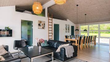 Una sala de estar moderna con un sofá de cuero negro, una mesa de comedor con sillas y un ventanal que ofrece vistas al exterior.