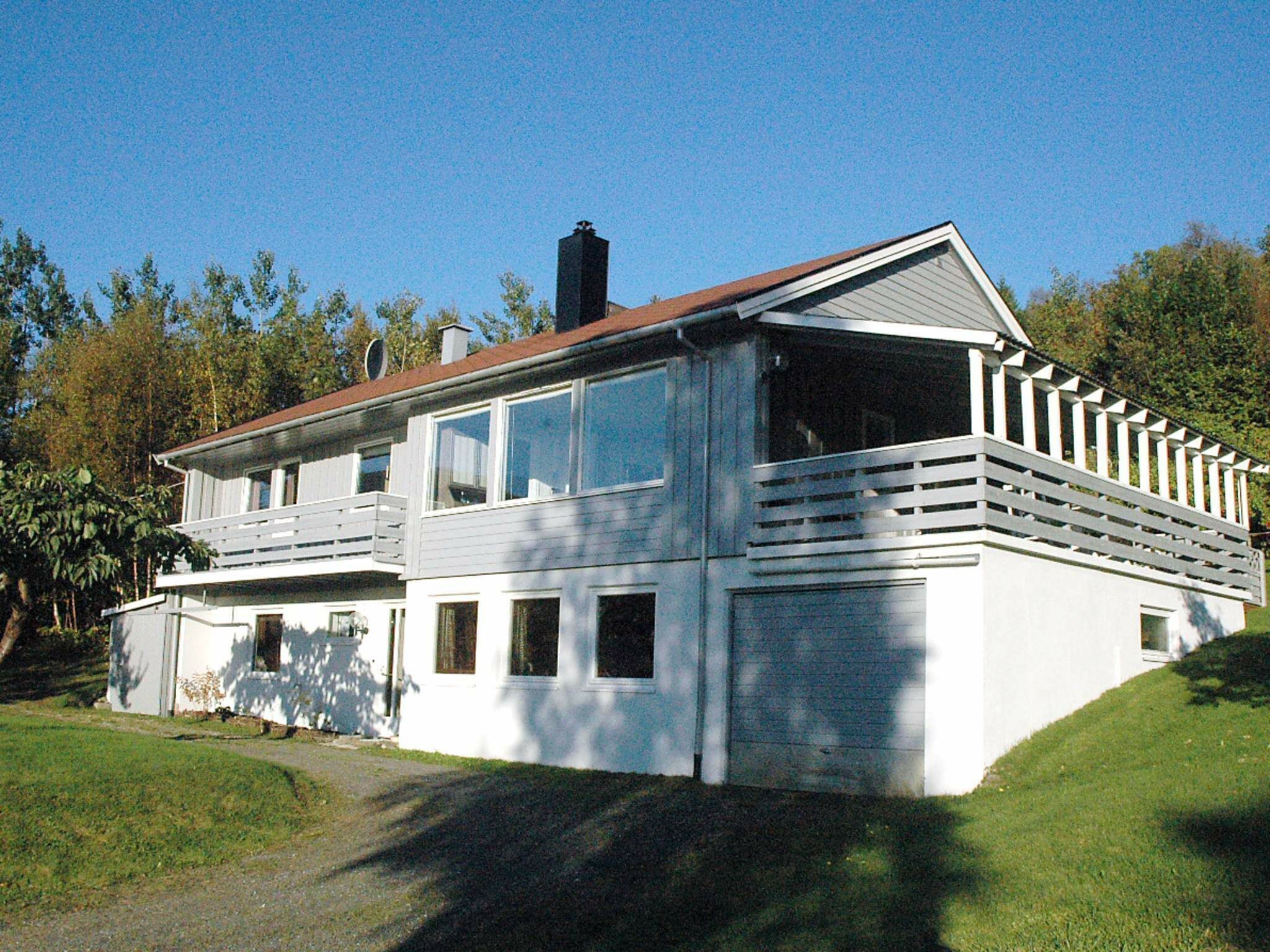 A two-story house with a large balcony, a chimney, and a garage.