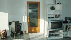 A living room with a wooden door, a white entertainment unit, and a glass coffee table. - Holiday Home in Åfarnes (Rauma)