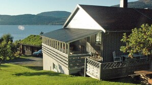 A house with a covered porch, a garage, and a view of a lake and mountains. - Holiday Home in Åfarnes (Rauma)